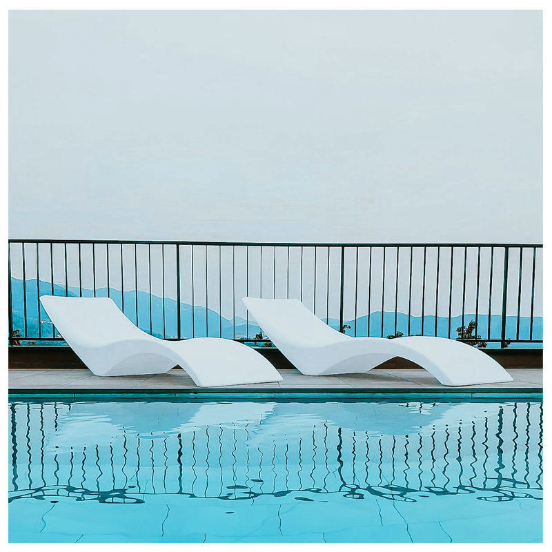 Outdoor white plastic lounge chairs by a pool